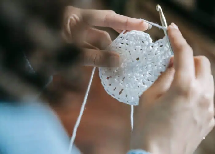 Hand crocheting a heart-shaped ornament.