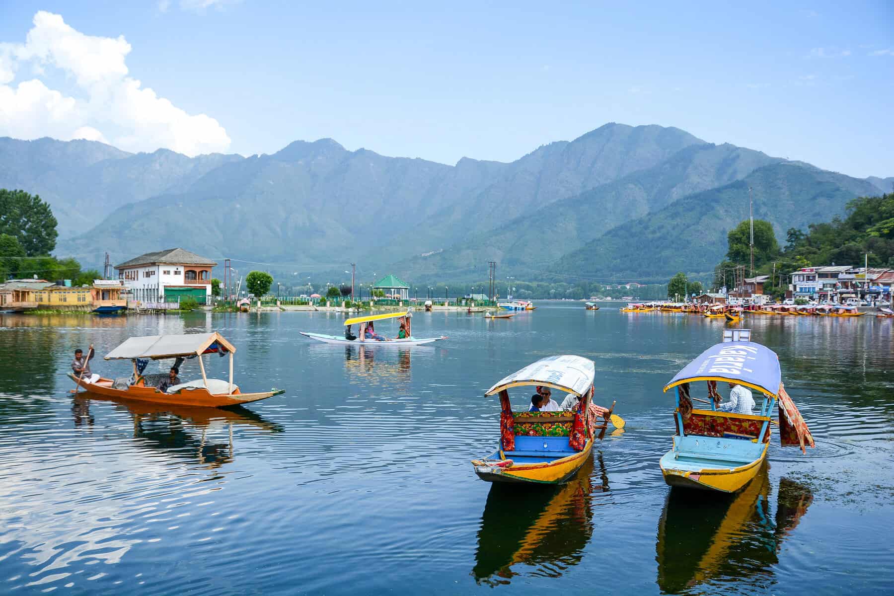 Colorful boats floating on calm waters with mountain views in the background.