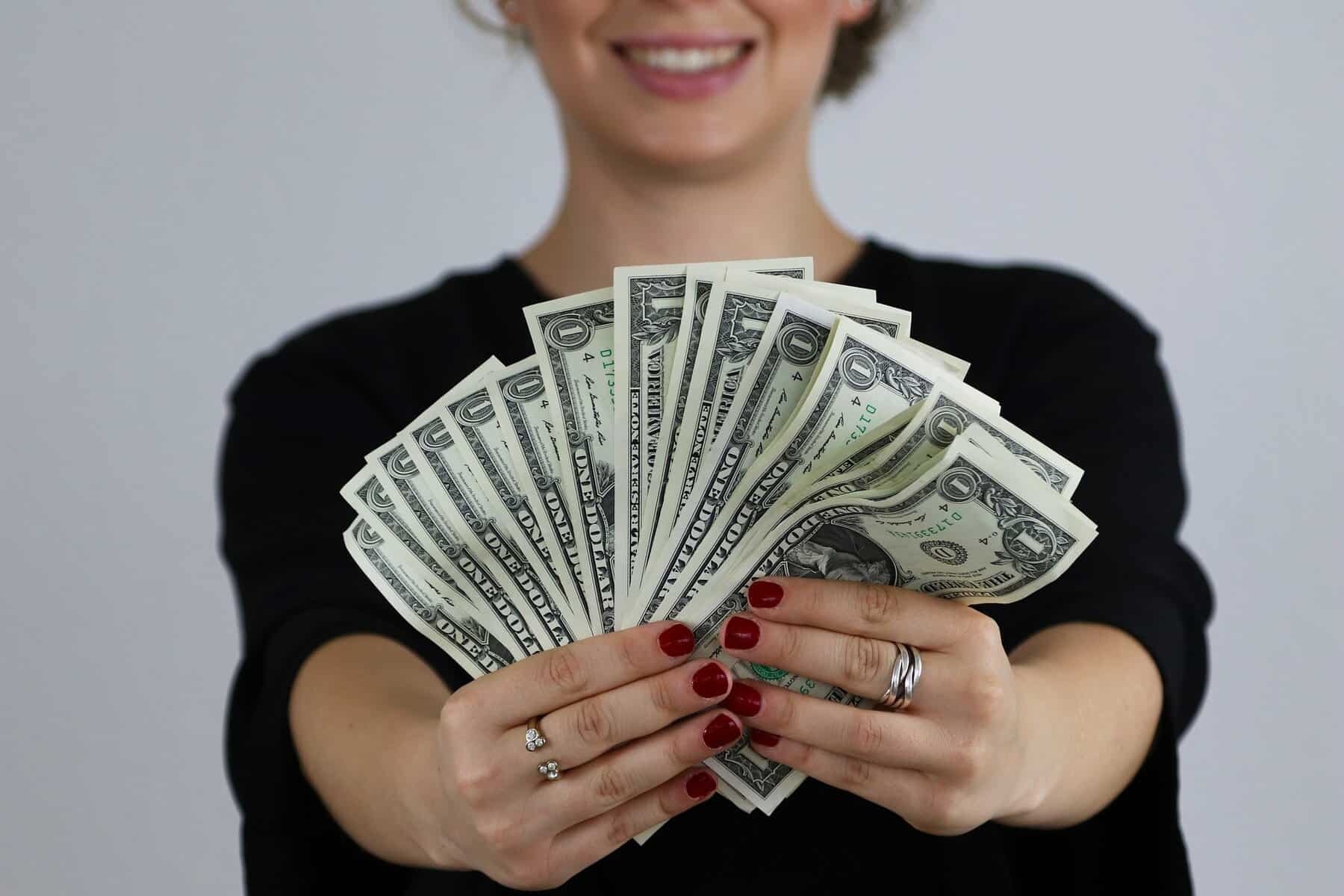 Home Icy 45 Money fan spread in woman’s hands with red nails and rings for wealth and prosperity.
