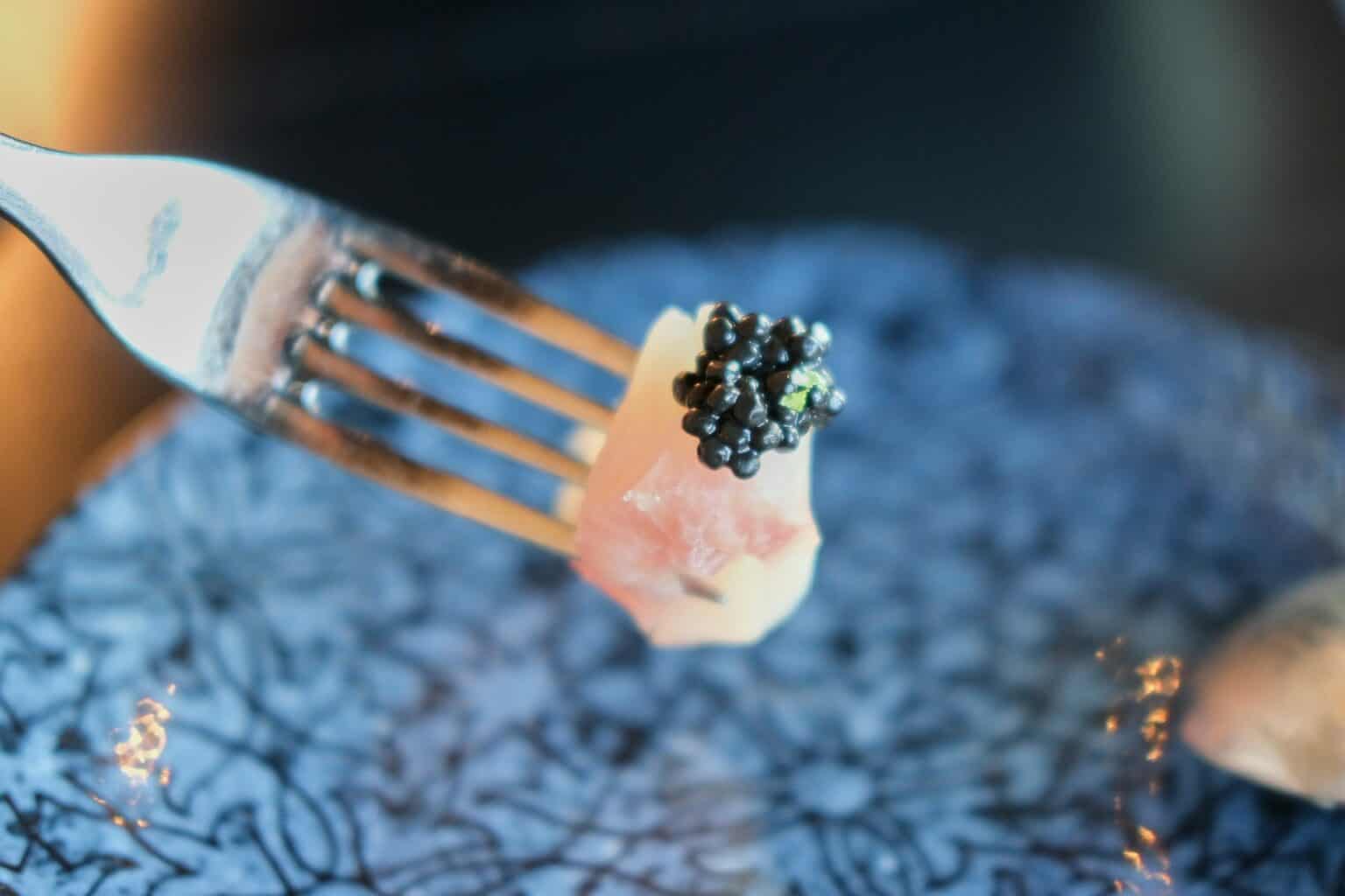 Close-up of black caviar on fork, fine dining, gourmet seafood, luxury appetizer.