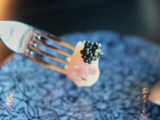 Close-up of black caviar on fork, fine dining, gourmet seafood, luxury appetizer.