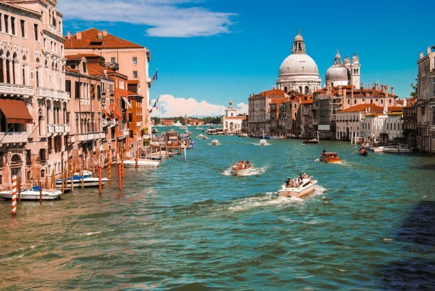 Italy Travel Guide: 10 Destinations That Define La Dolce Vita 1 Bright blue sky with boats cruising through the colorful waterway.