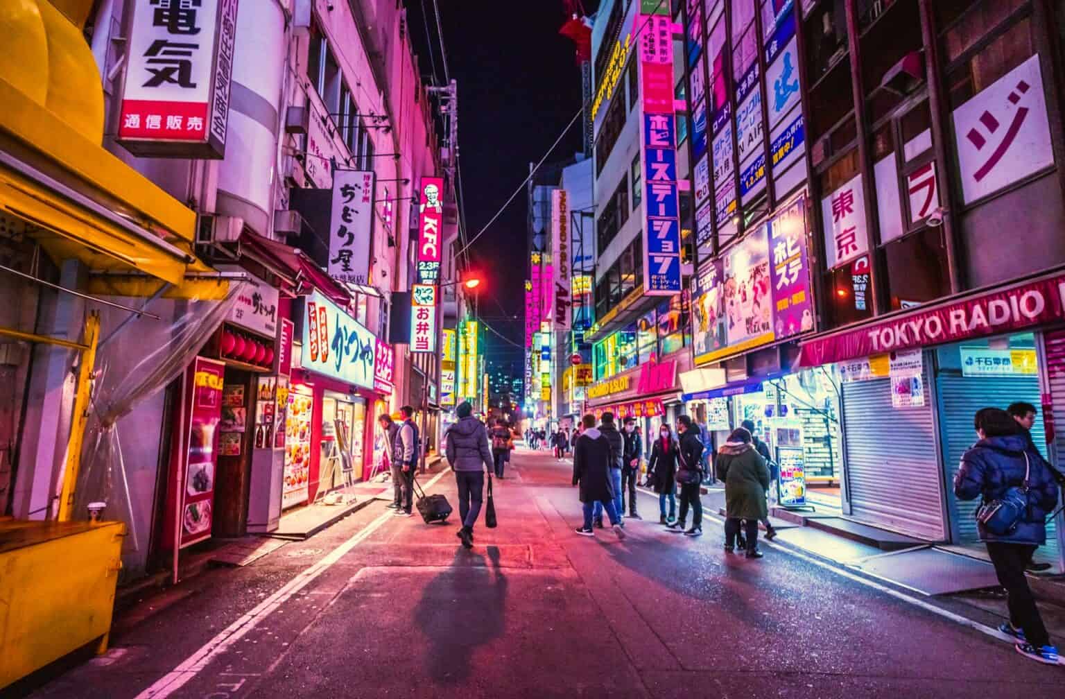 Colorful Tokyo nightlife with illuminated signs and people shopping at night.