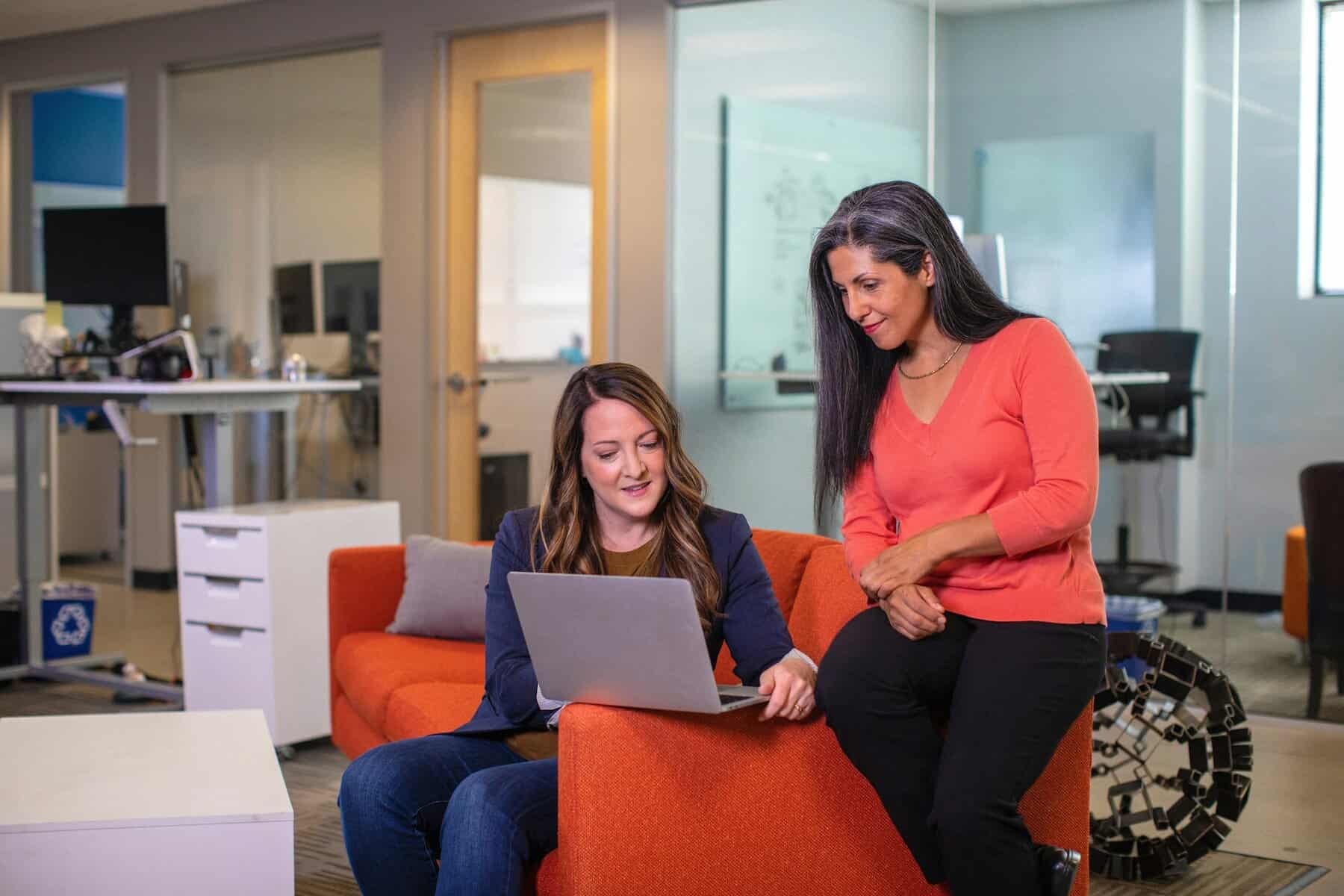 Home Icy 45 Women working together in a vibrant, contemporary office environment with a laptop.