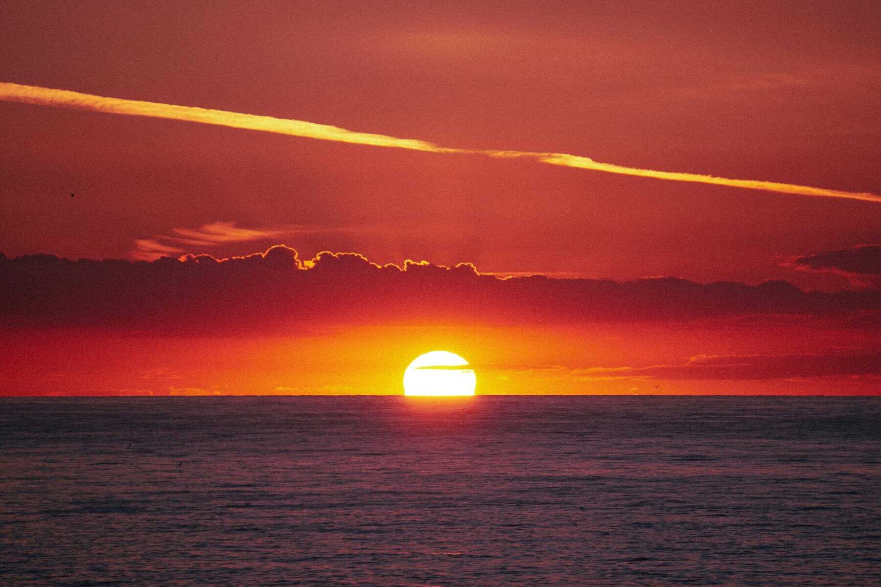 Sunset over the ocean with colorful sky and calm waters, ideal for travel and nature photography, capturing peaceful moments.