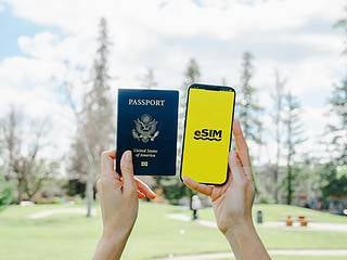 US passport and eSIM on phone for international travel in outdoor park setting.