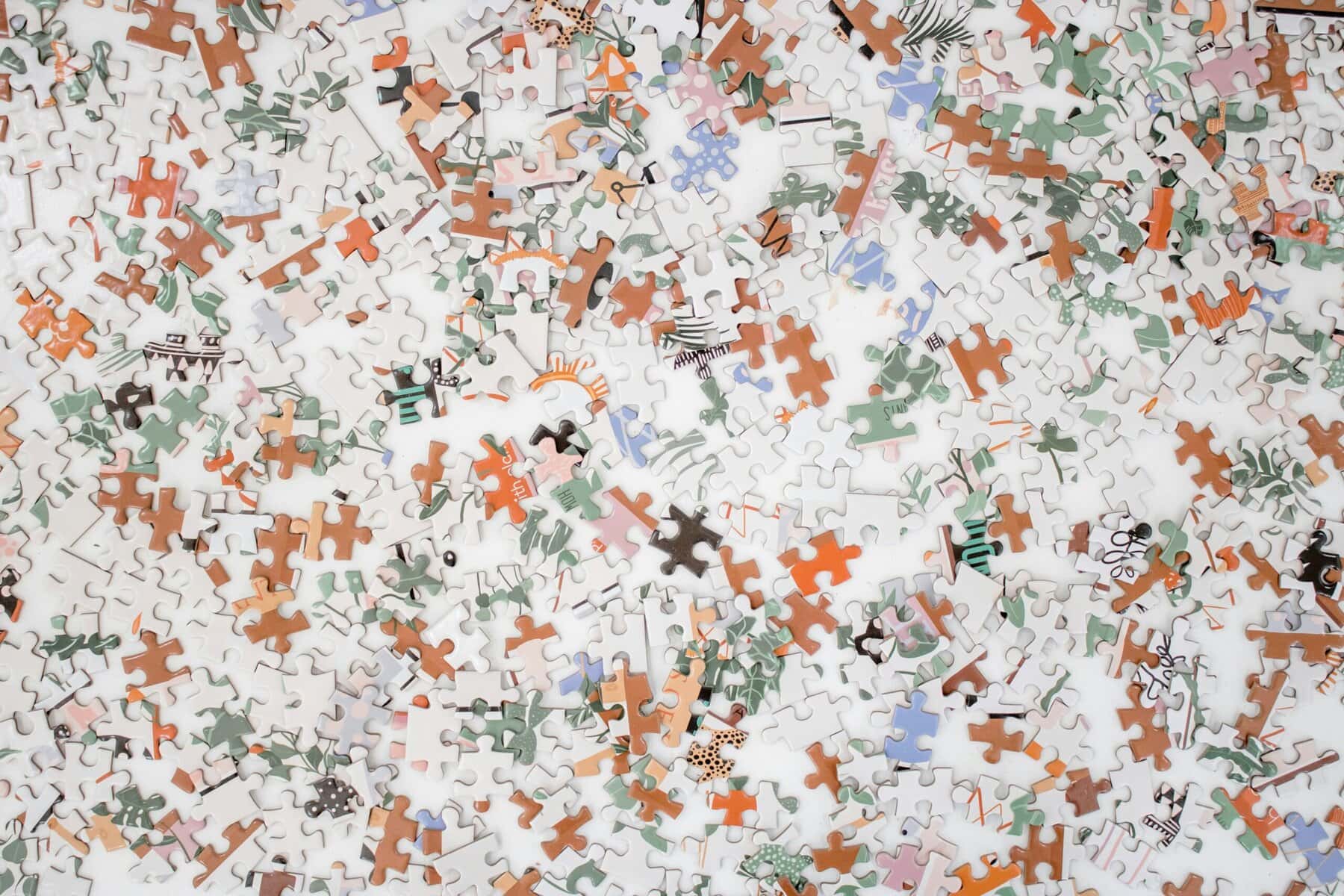 Colorful puzzle pieces with various patterns and shapes scattered on a white surface.