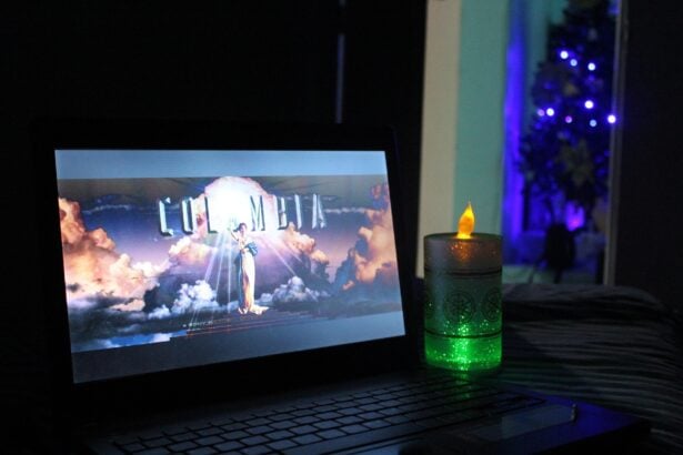 Alt text: Laptop screen displaying a movie poster with clouds, illuminated in a dark room with a candle beside it.