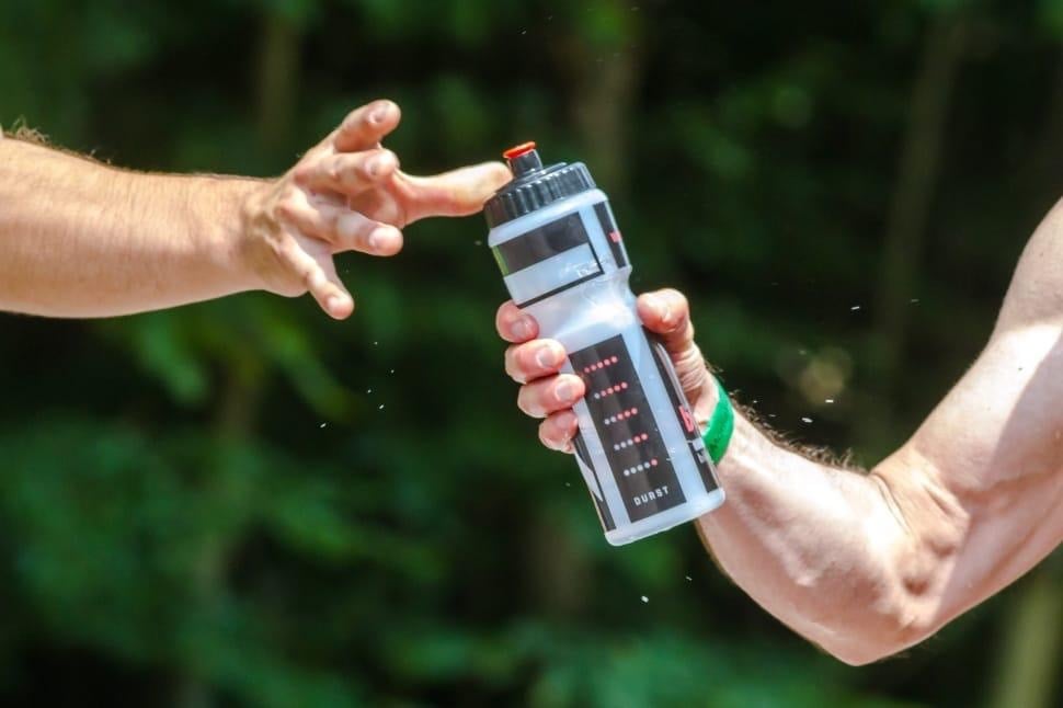 How Sports and Strategic Play Enhance Focus and Mental Resilience 2 Person handing over a water bottle outdoors, promoting hydration and health.